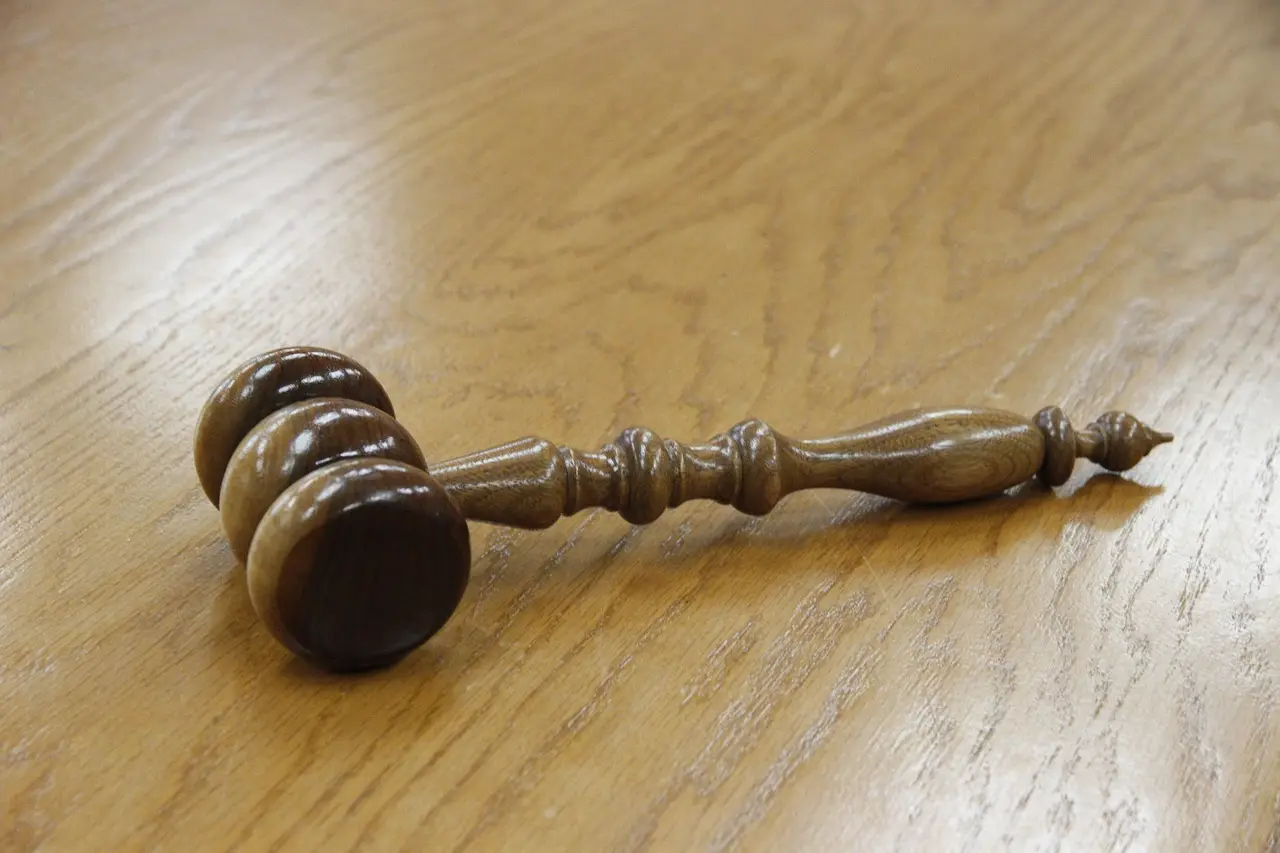 A wooden gavel lying on a bare wooden desk